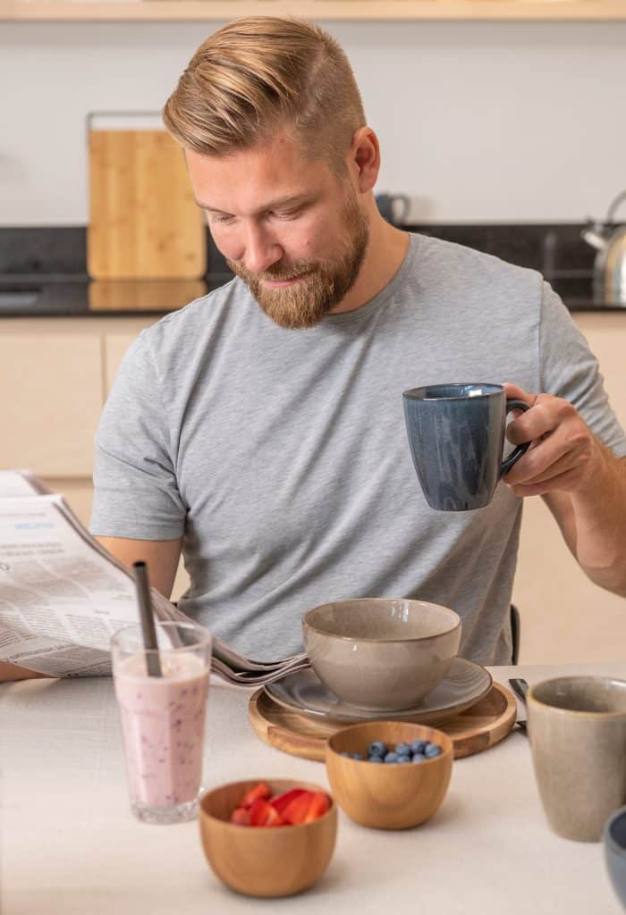 Mies juo aamiaispöydässä kahvia Tones-sarjan mukista.